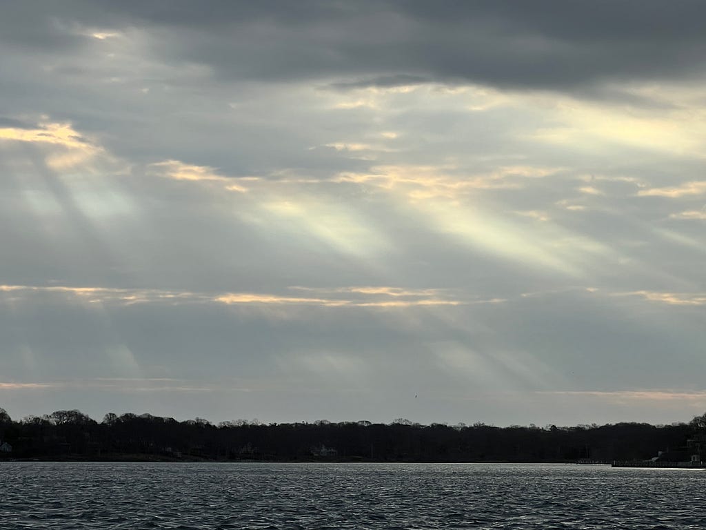 photo of sunrays through clouds over water