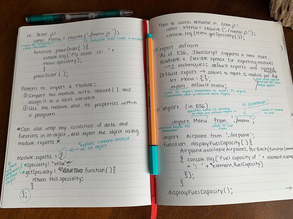 An open notebook with handwritten notes on using modules in JS, with a pen lying between pages