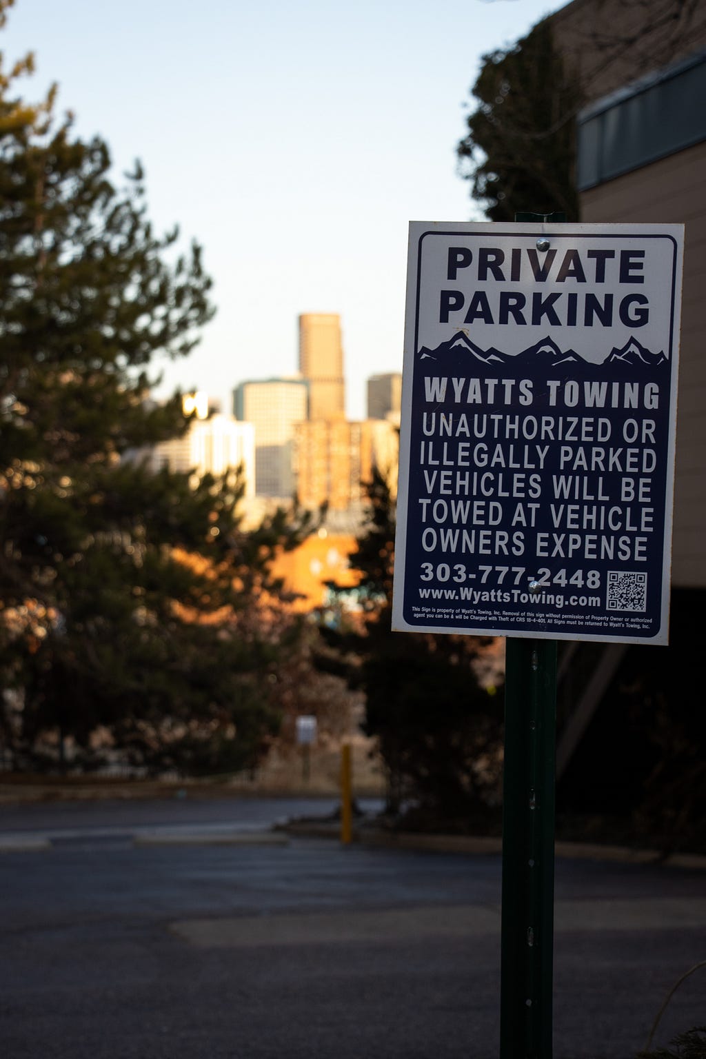 A Wyatts Towing sign posted at the entrance of a private parking lot near downtown Denver