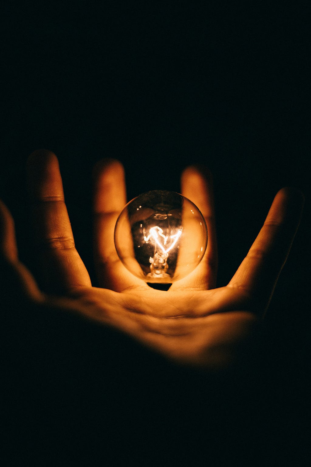 hand in the dark holding a bulb with a spark