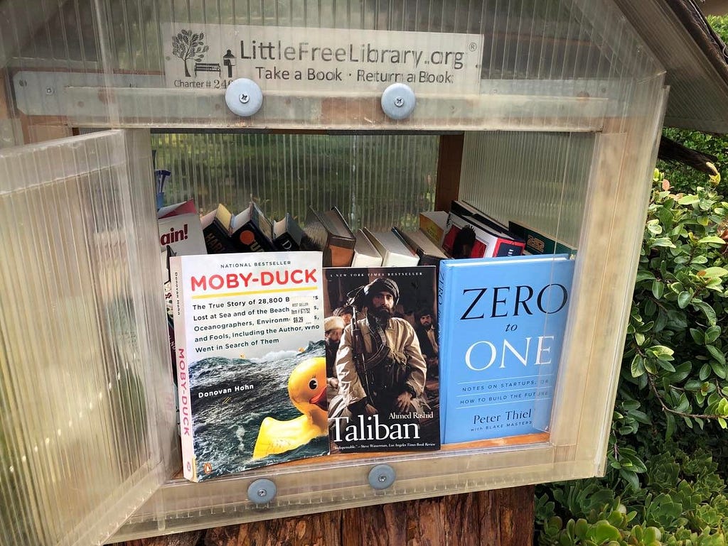 three books in little library Moby-Duck, Taliban, Zero to One