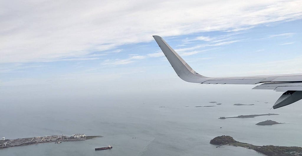 A photo from the airplane with the wings showing in the right and ocean in the background