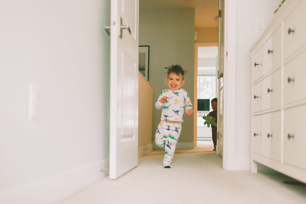 Happy little boy running through the halls of his house with a friend.