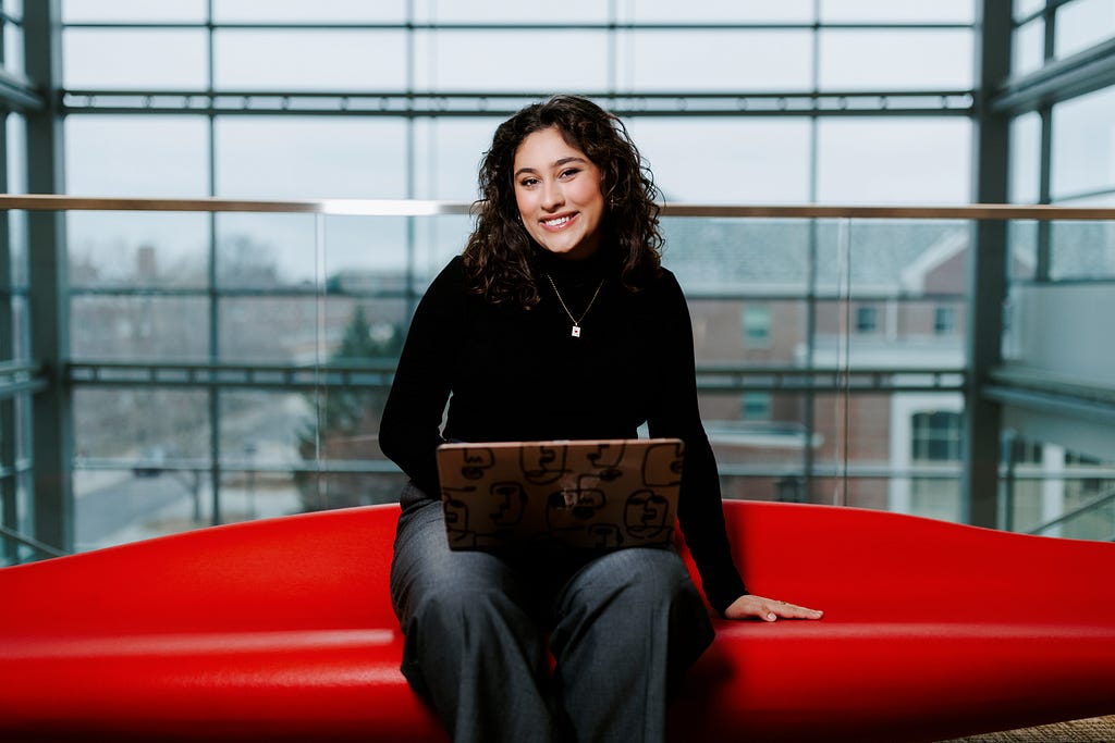Ritsa poses for a photo on a red bench in Howard L. Hawks Hall