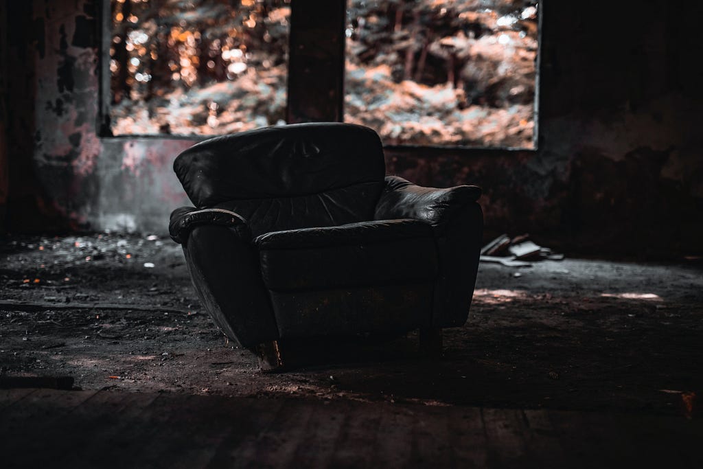a worn-out leather armchair in an abandoned, deteriorating cabin