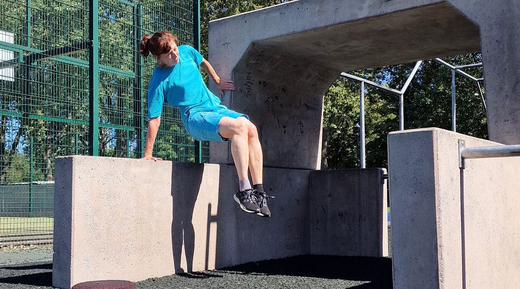 Woman doing a corner vault over a hip-high concrete wall