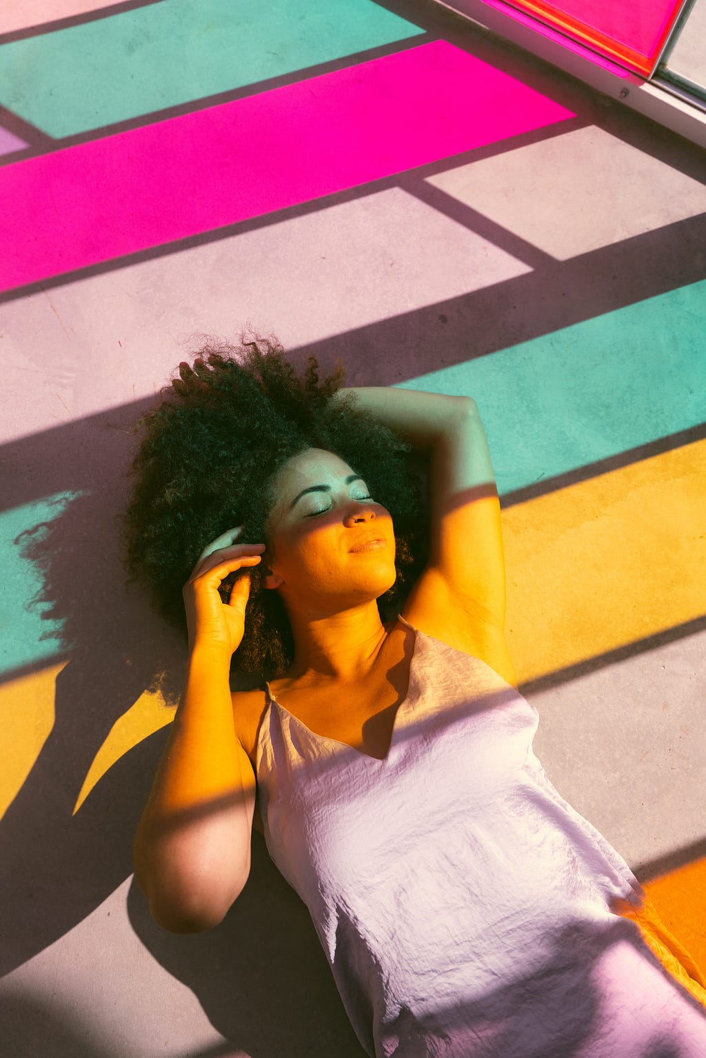 A calm and relaxed woman laying down with colored reflective light shining down on her