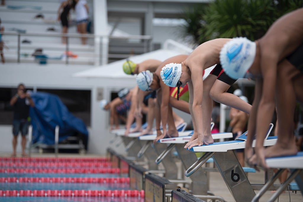 A group of men standing on the starting blocks of a swim race