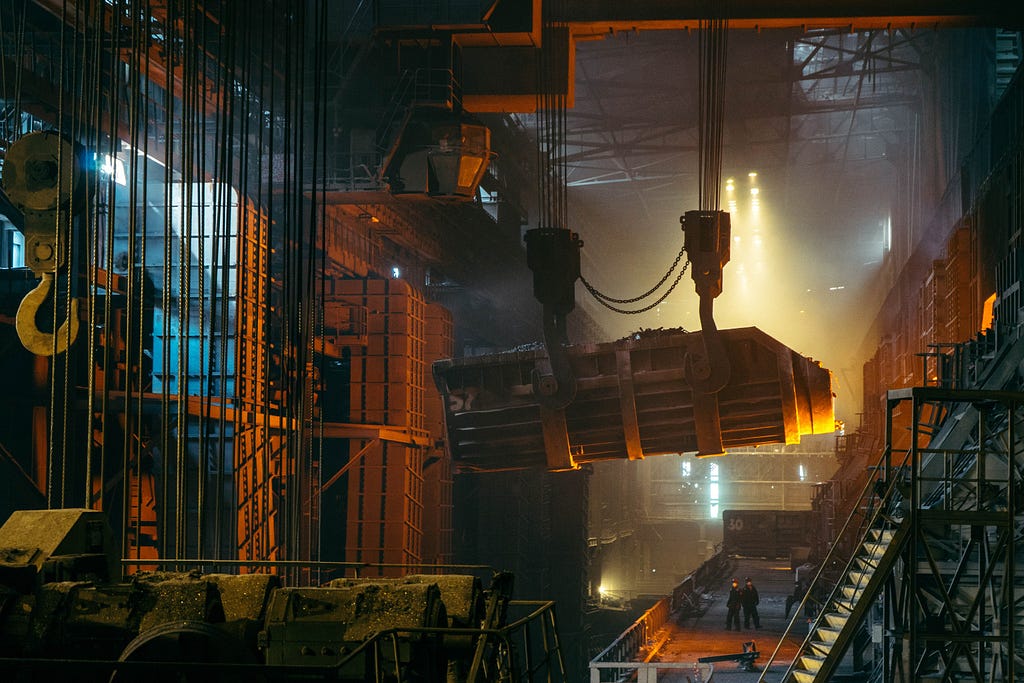 Heaving machinery moving on chains and pulleys in large industrial space.