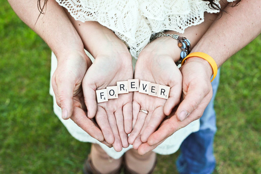Couple’s hands holding the word “Forever”
