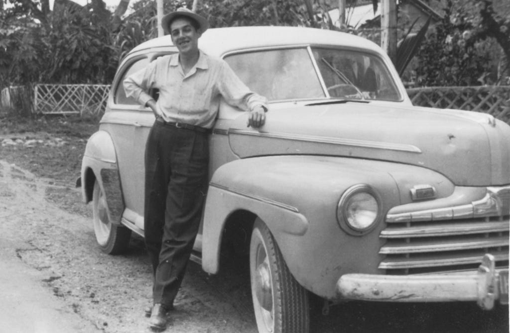 Photo of Alvaro B. Matiz posing with a 1946 Ford on the side of the road.