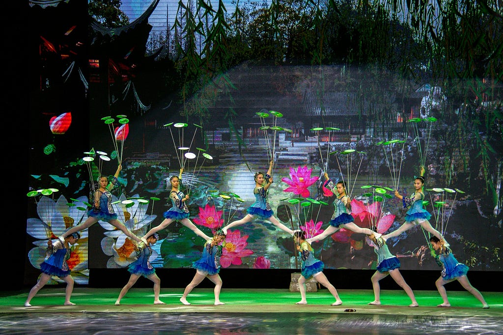 Female acrobats all spinning plates and balancing on each other as a part of the Chinese acrobatic troupe in Beijing
