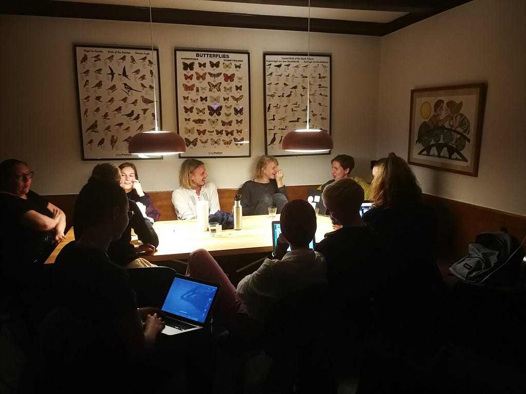 People sitting around a table laughing and working on laptops