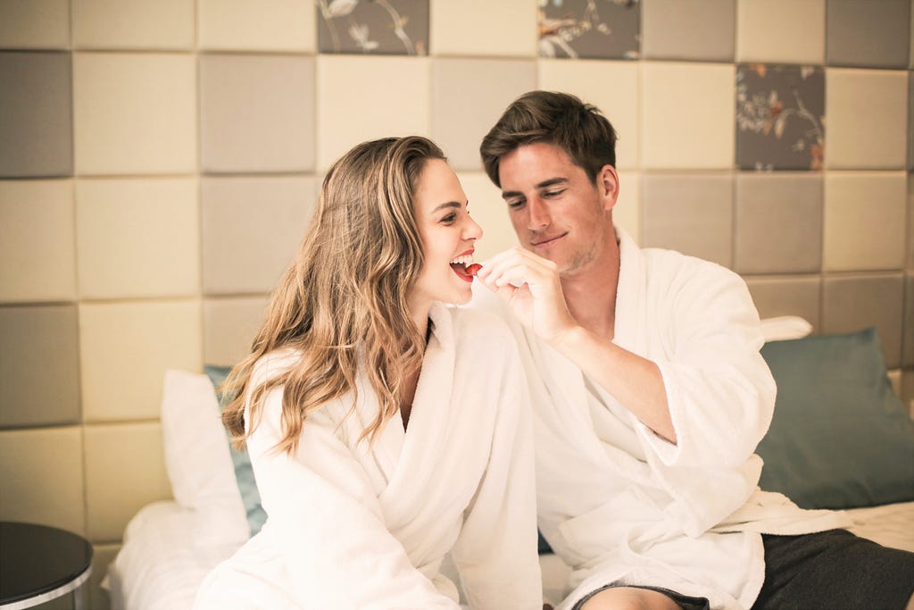 Affectionate couple on the bed enjoying fresh fruit.