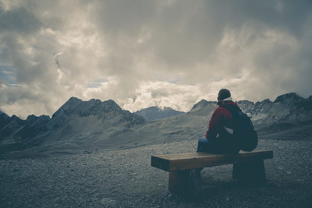 picture of a man seating alone view the moutains