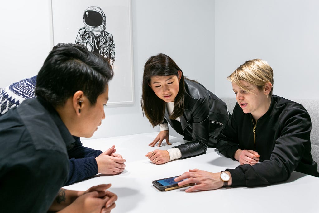 Four people focusing on a smartphone