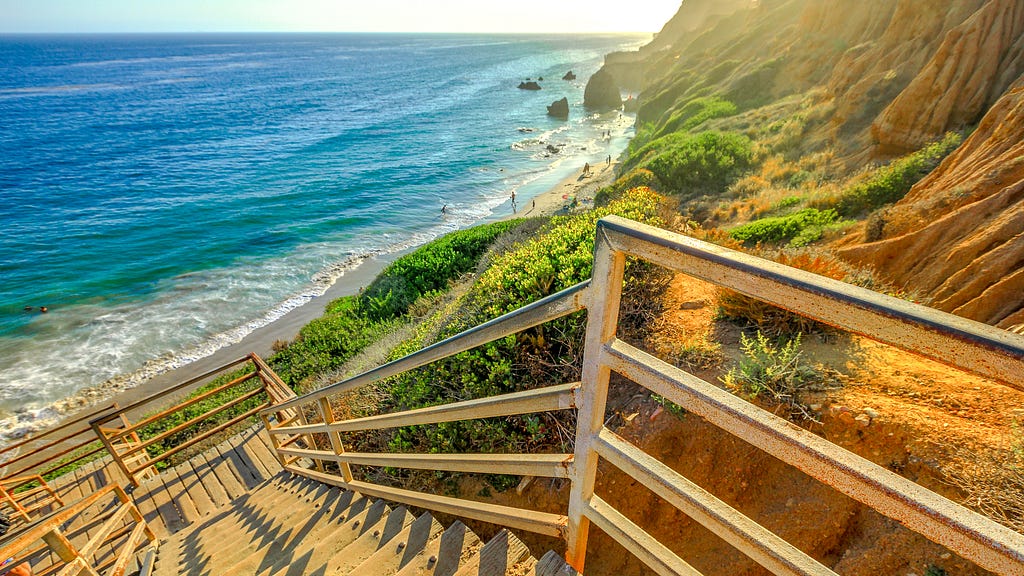 Secret secluded beach in Malibu, Los Angeles, California. Clear day with staircase leading down to a beautiful sandy beach with amazing rock formations.