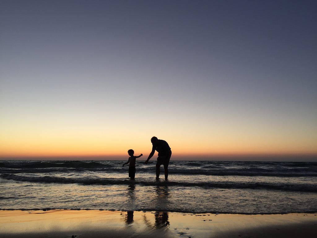 A father and son silhouetted on the beach — photo by Dvir Adler on Unsplash.