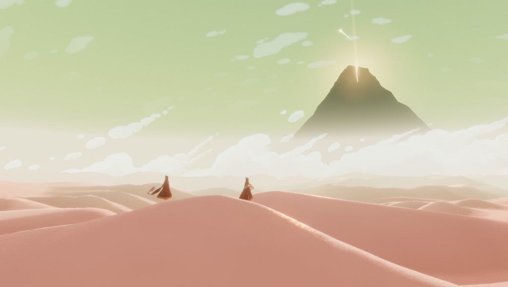 Screenshot from Journey. Two players stand together on a sand dune looking at a far-away mountain.
