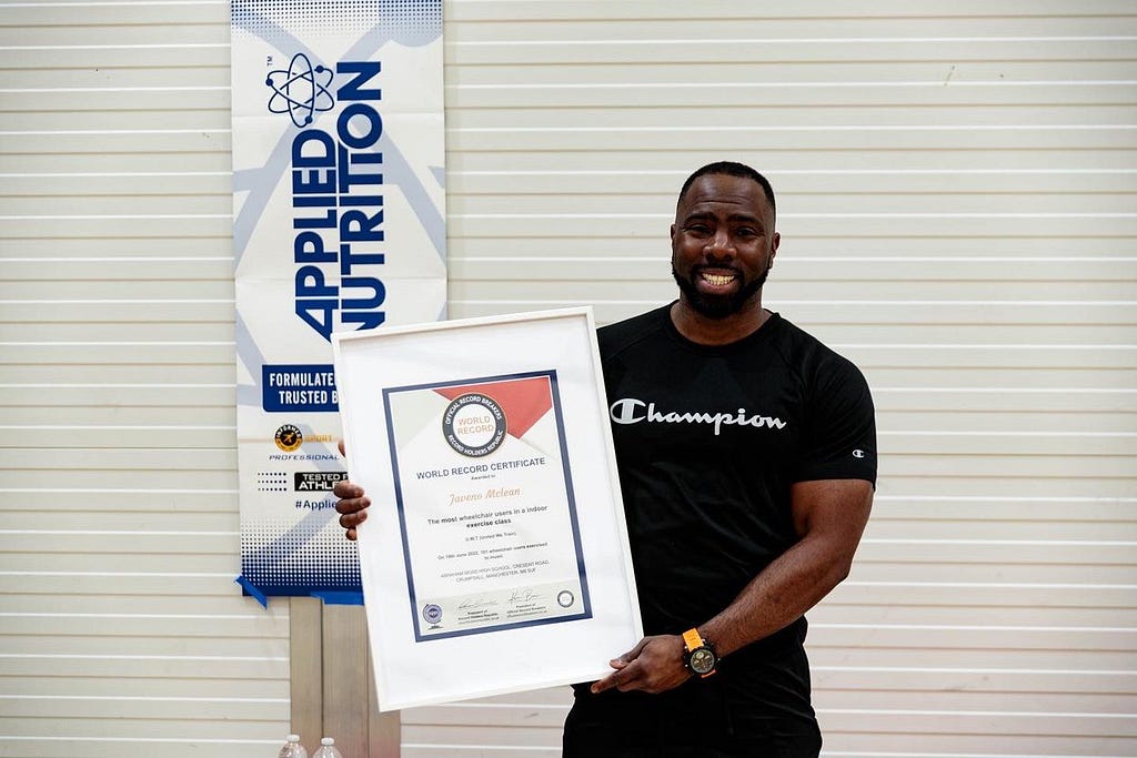 A man holding a certificate — Pictured: Javeno Mclean. Image shows world record for ‘the most wheelchair users in an indoor exercise class.’ This will accompany a blog post by Chantelle Roberts at Sopfistudios.com