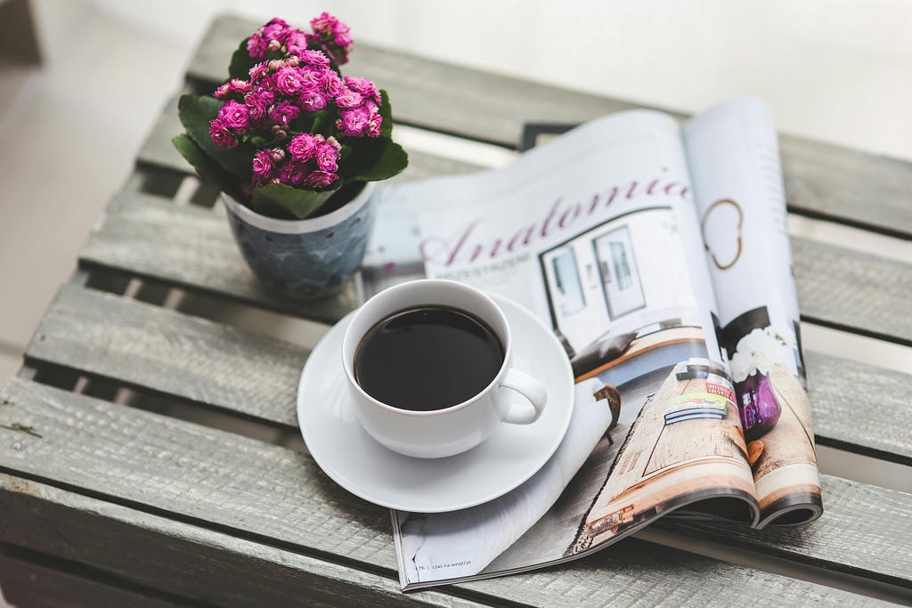 Image of table with flowers, newspaper and coffee on it to illustrate post