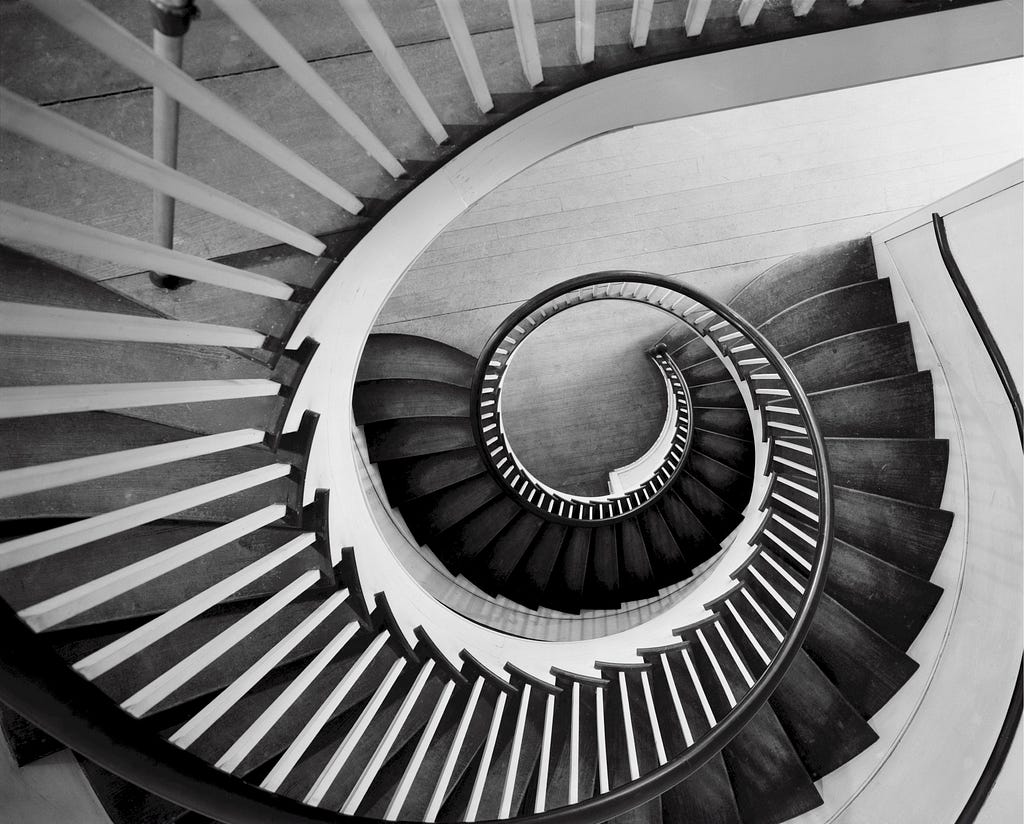A black and white image from above of a spiral staircase.