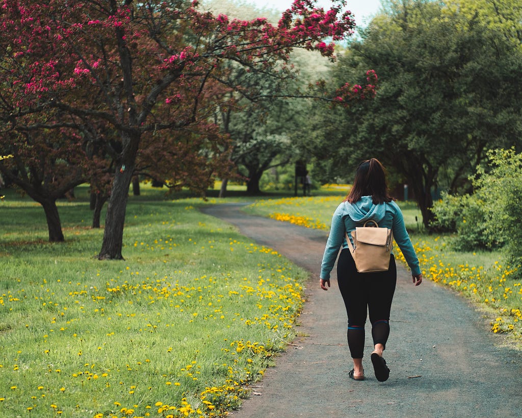 woman with backpack walking on a trail