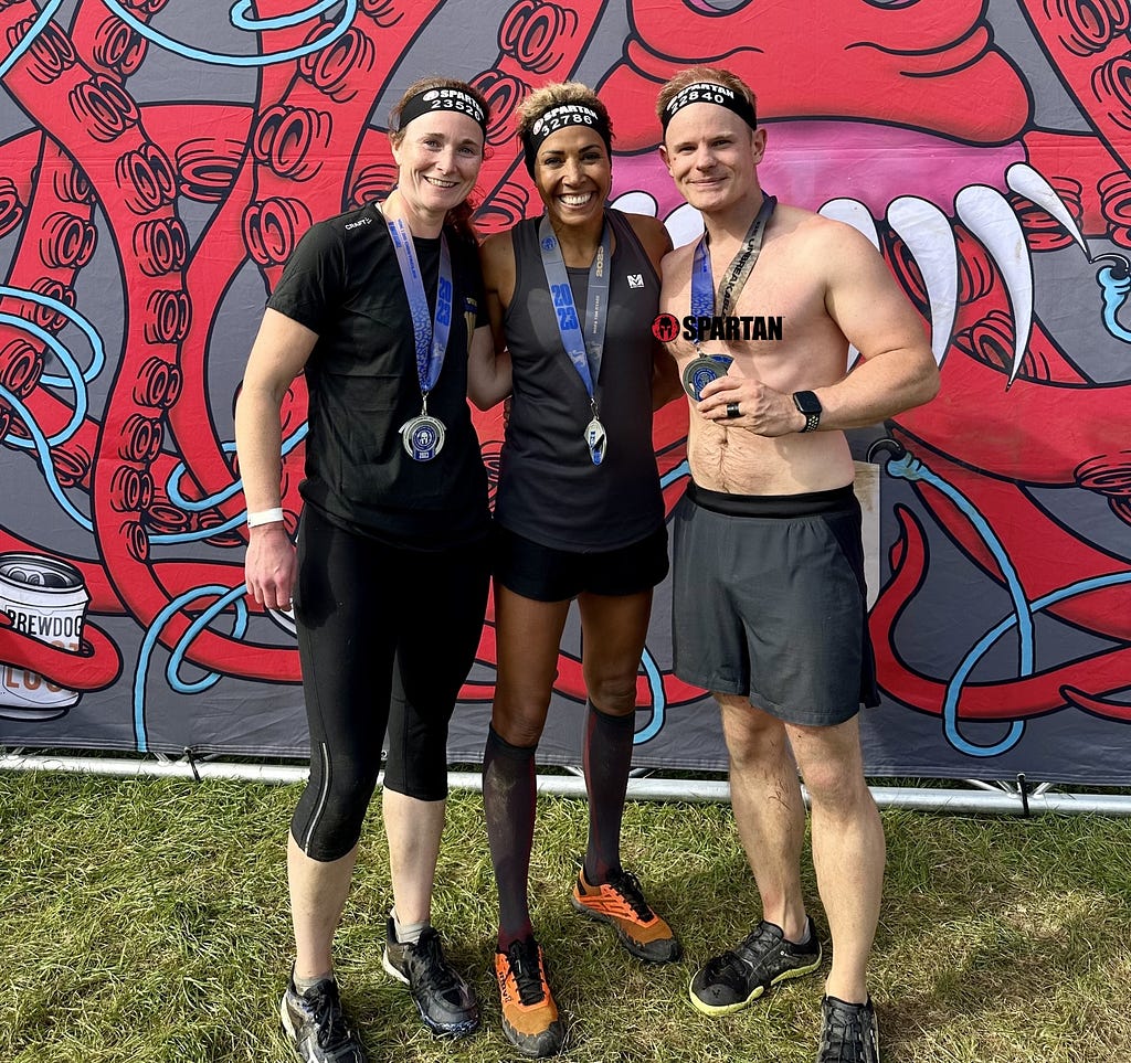 Photo of Sam Surridge, Dame Kelly Holmes, and Rico Surridge on the finish line of the London 2023 Spartan Super Obsticle Race.