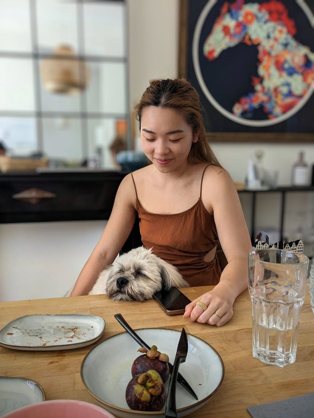 Michelle with a dog on her lap, sitting at a dining table