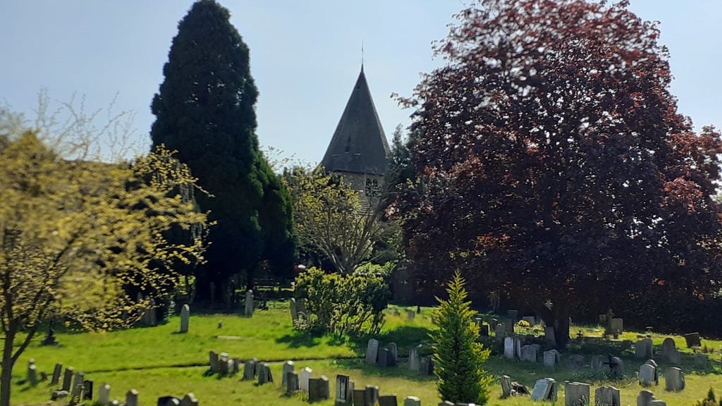 A large graveyard with trees and am old church in the background