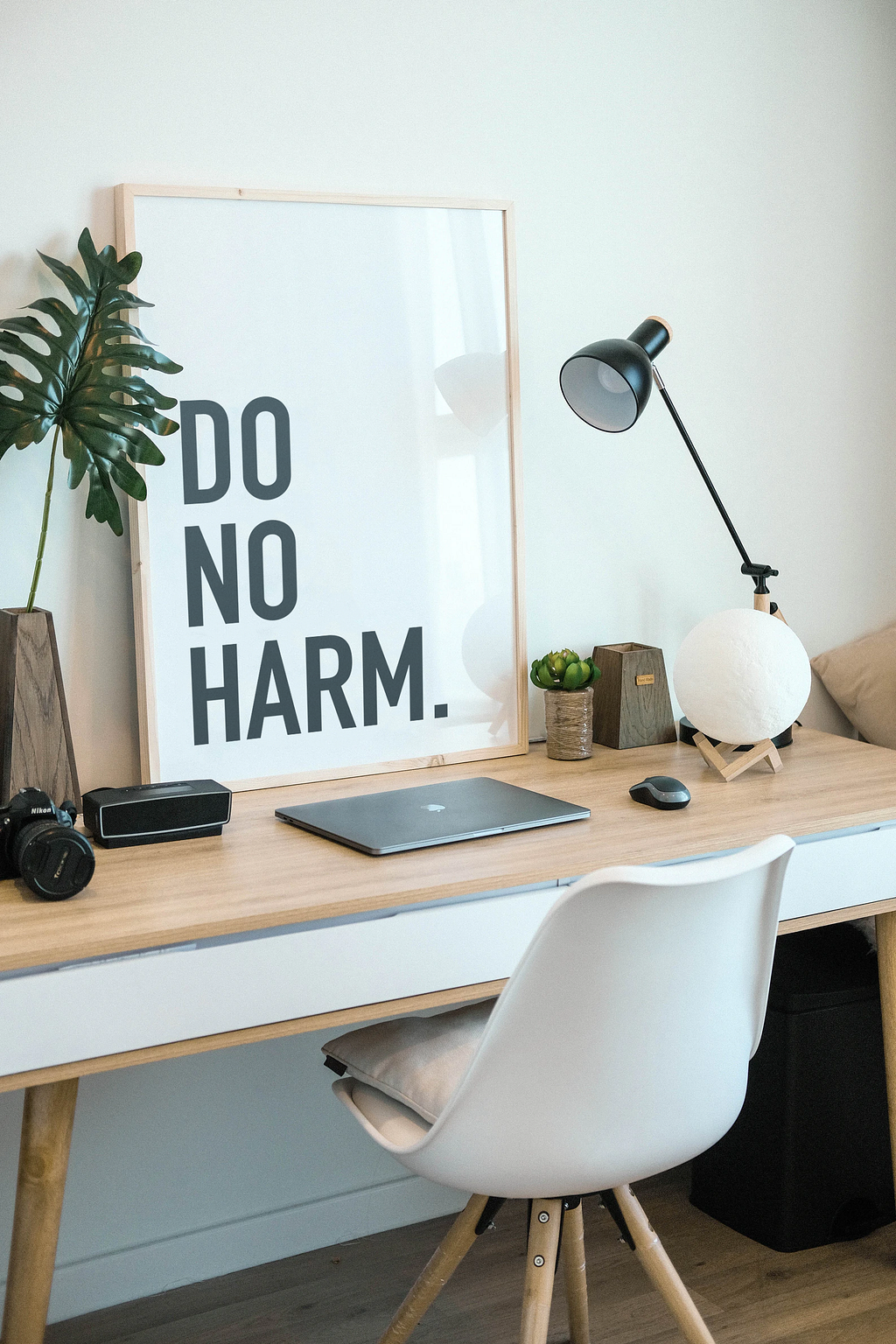 A desk with a laptop and a “Do no harm” sign.