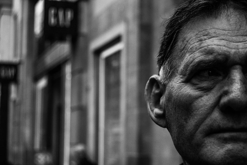 closeup of elderly man’s face walking down a street in London
