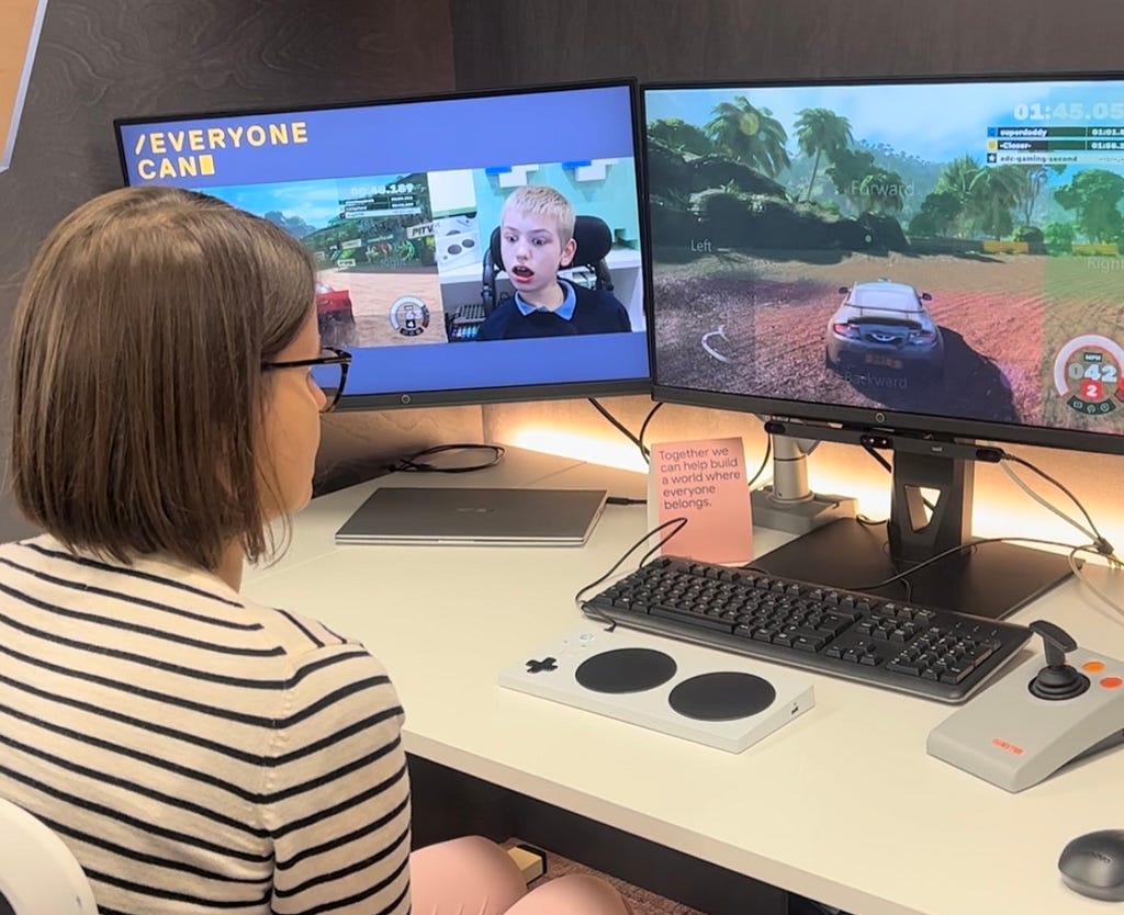 Karolina sits in front of a screen with a racing car on it playing a game where the direction of the car is controlled by tracking your eye movement.