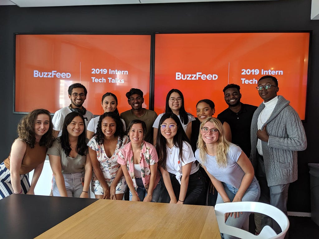 A phot of BuzzFeed summer interns standing in front of a powerpoint presentation that reads “BuzzFeed 2019 Intern Tech Talks”