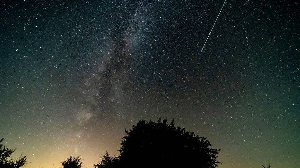 The night sky with a meteor shooting across the middle.