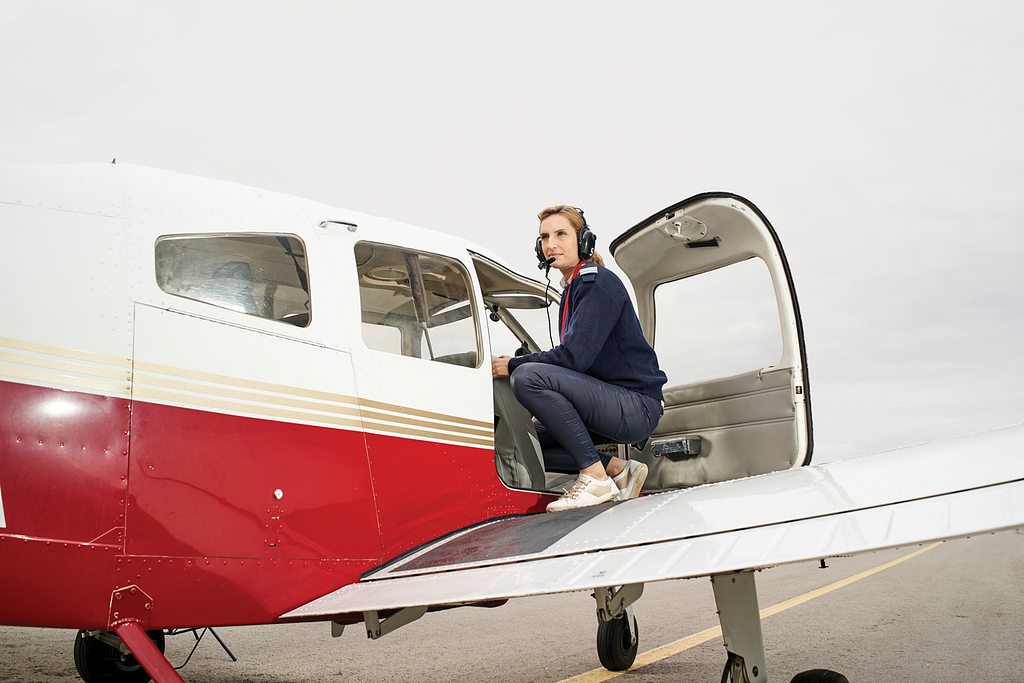 Photo of a women on the wing of a small airplane.