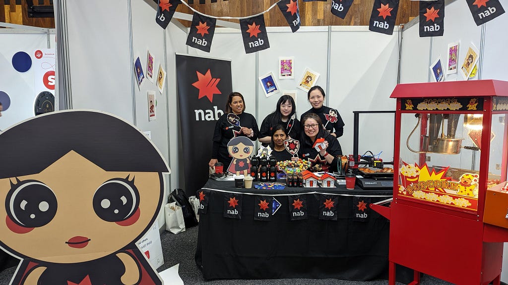 5 women standing behind a table in a NAB-branded booth