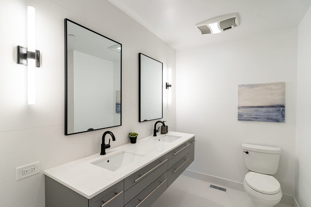 Remodeled bathroom done in white with black trim and accents of blue and silver