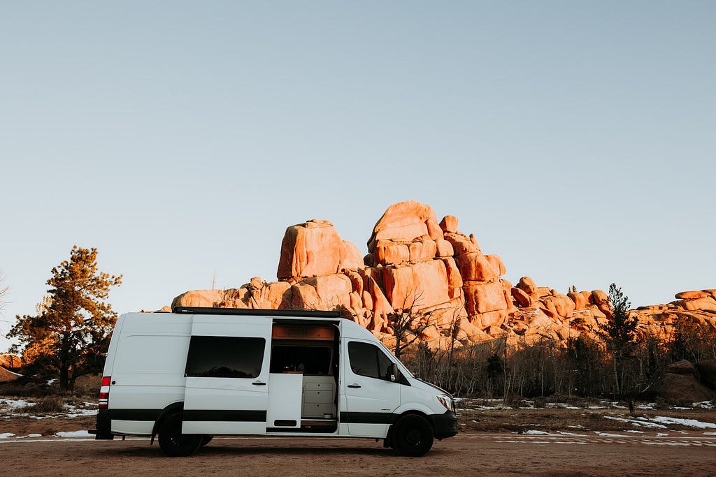 White Mercedes Sprinter camper against backdrop of rocks