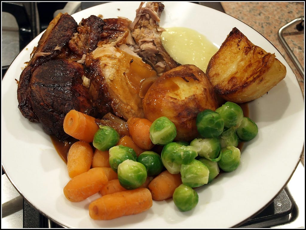 photo of a plate of chicken with gravy carrots, potatoes and brussels sprouts