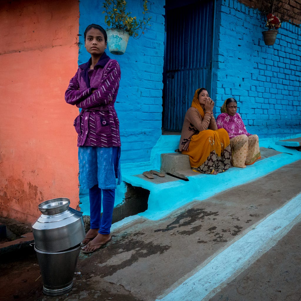 People around a brick house with colorful walls.