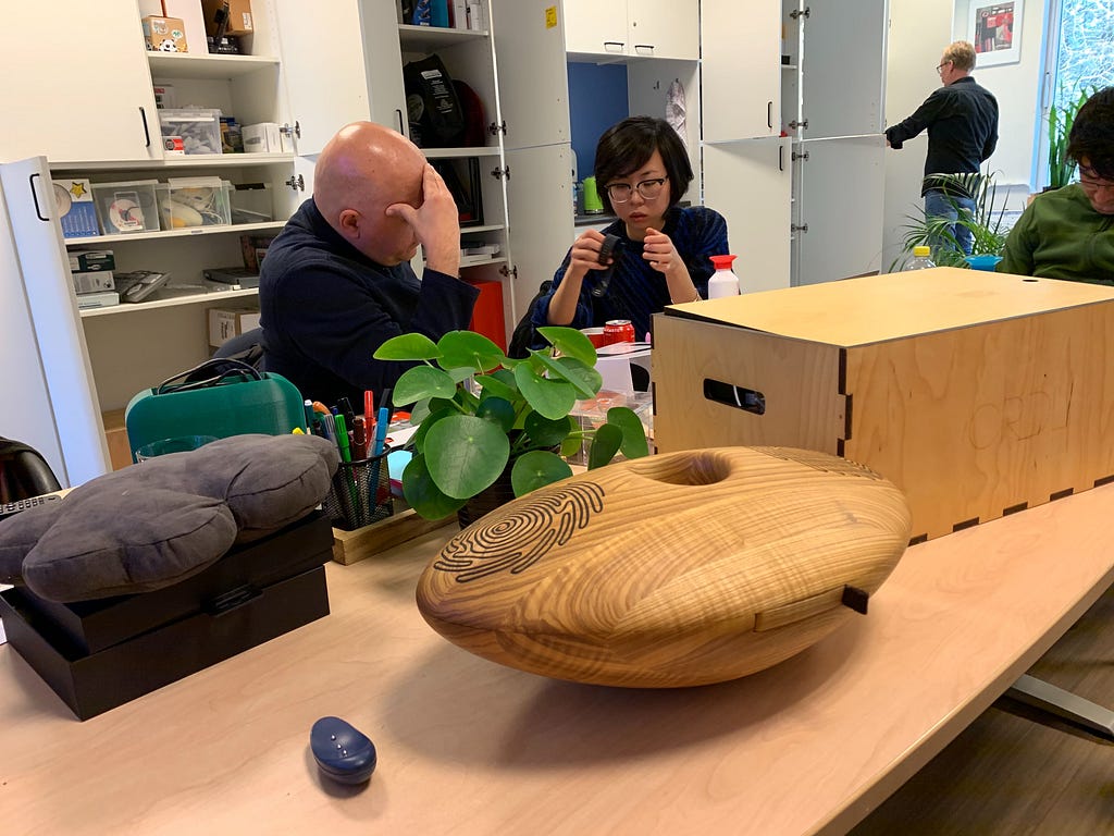 Two people looking at different technology for visually impaired people such as haptic bracelets and 3D sound speakers.