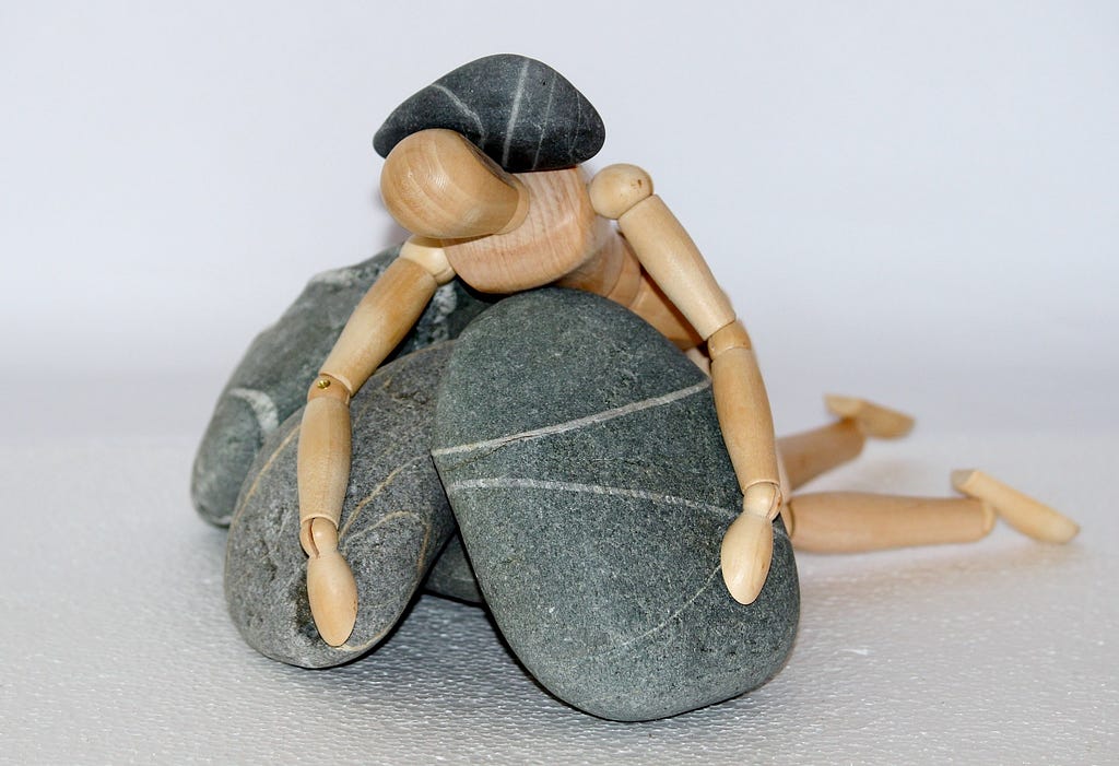 Wooden figure with rocks piled around