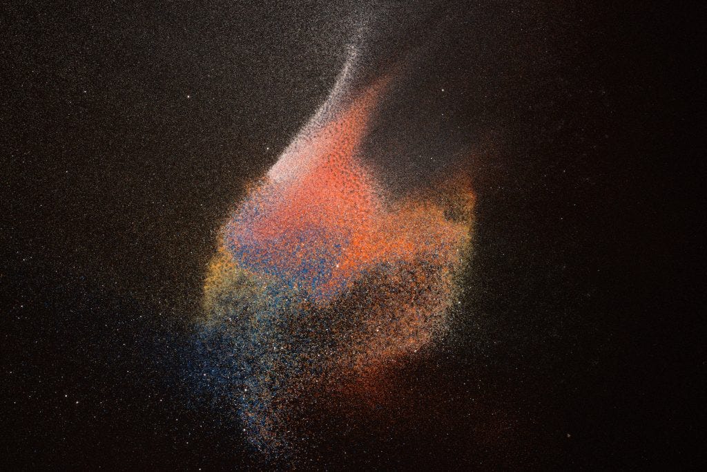 Abstract photograph of colored sand on black paper, created for healing by a medical doctor