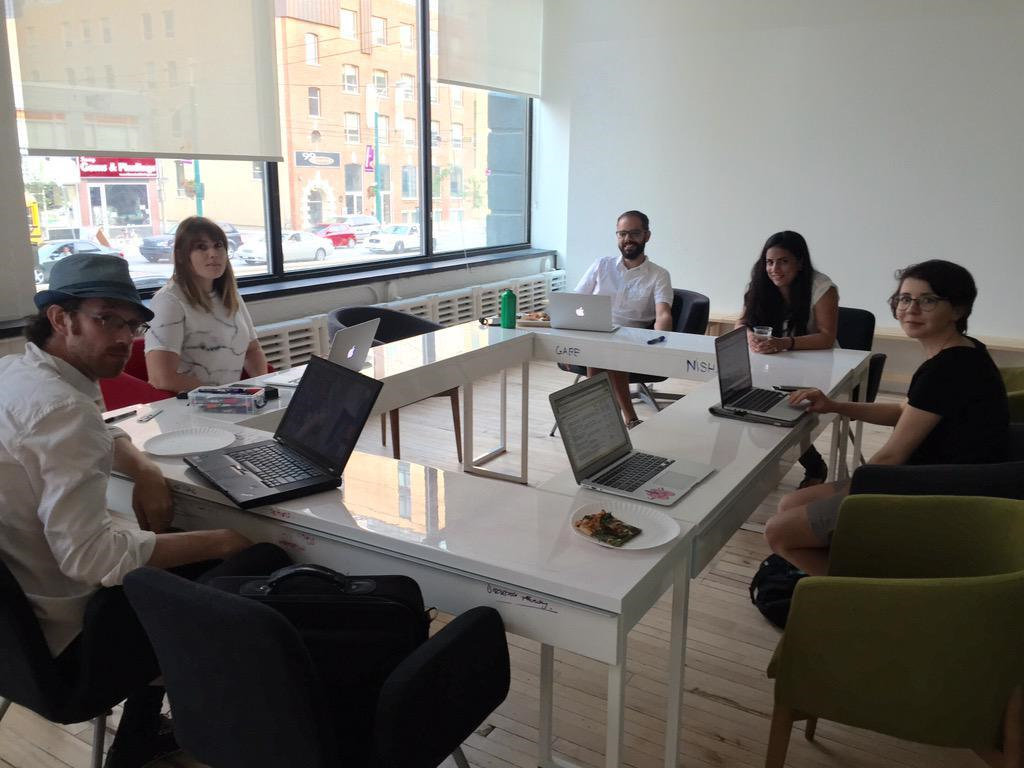 A photo taken in an office space downtown Toronto with six members of Civic Tech Toronto gathered around a table.