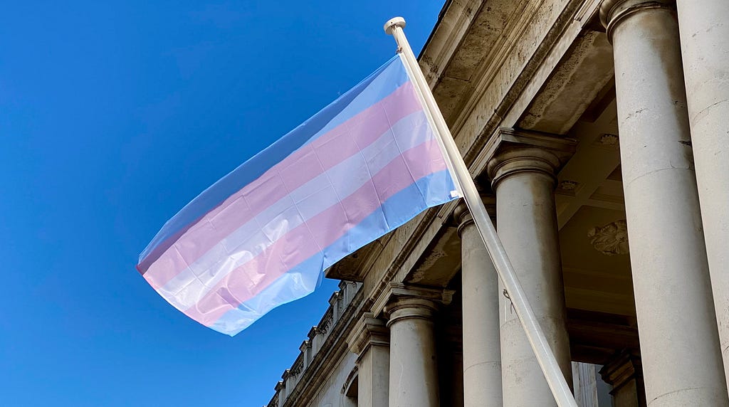 a trans flag fluttering in the sunshine at greenwhich uk