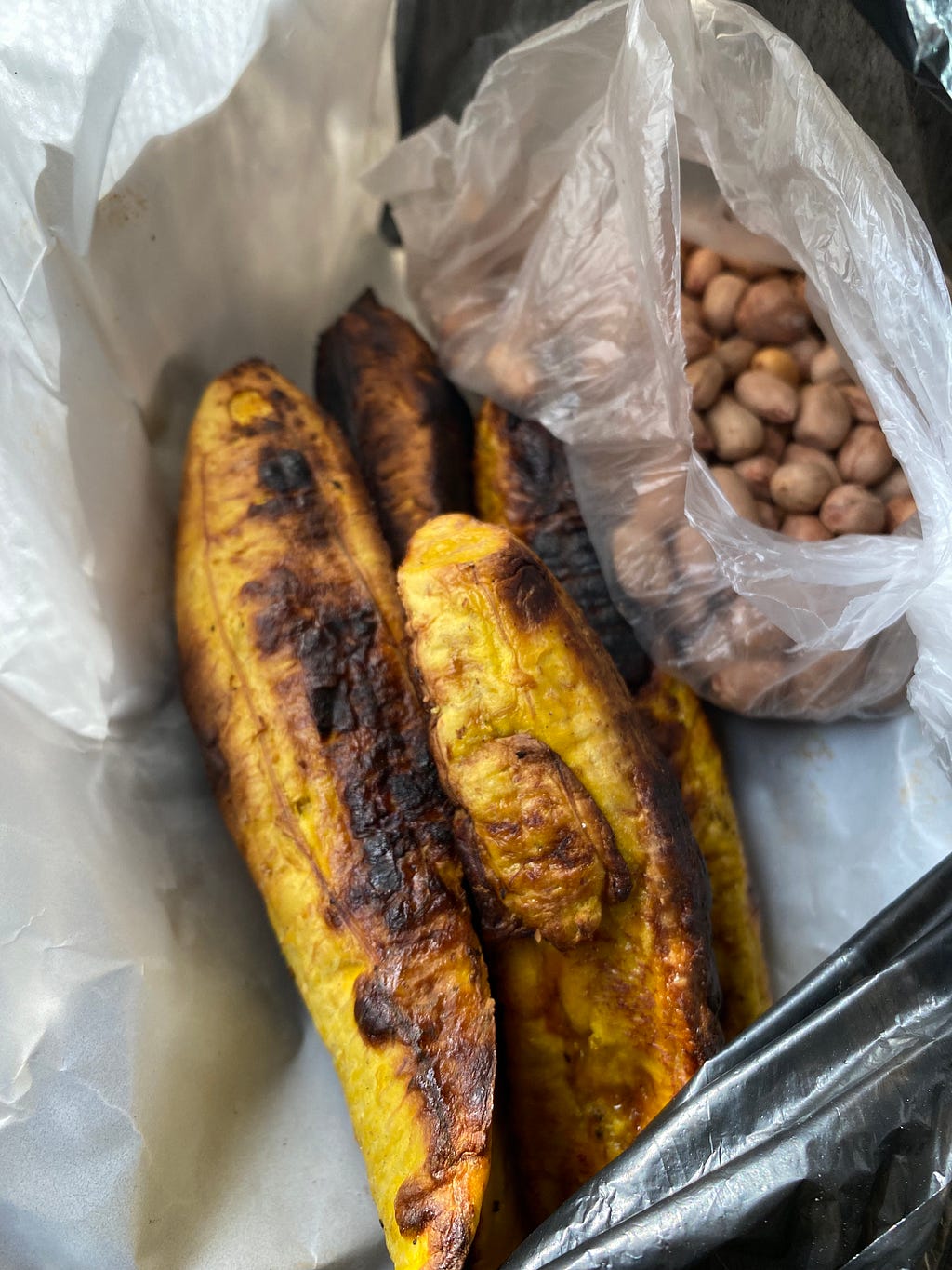 Grilled plantain and groundnuts, wrapped in paper. A street food delicacy.