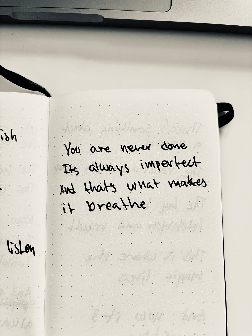 Picture of a handwritten poem in a small notebook: You’re never done. It’s always imperfect. And that’s what makes it breathe.
