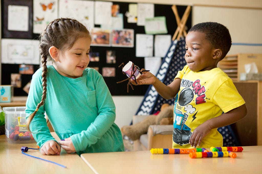 Two preschool-aged children, one girl and one boy, play together with art supplies.