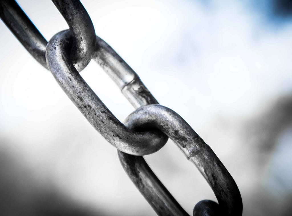 A slightly weathered steel chain in a diagonal line over a blurry, indistinct background.